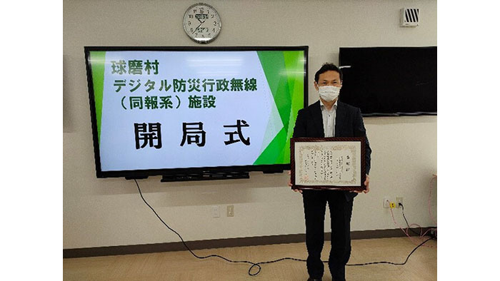 開局式での感謝状授与の様子　賞状をもって立つ男性